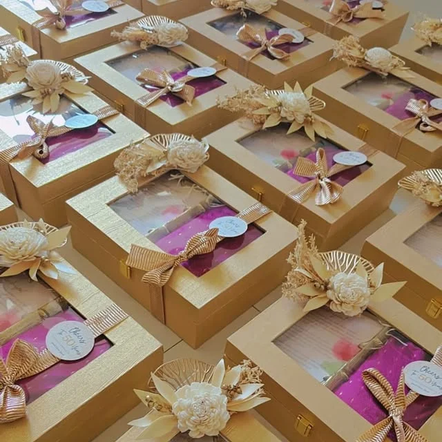 Gold favor boxes with window panels, tags and ribbons arranged as party keepsakes