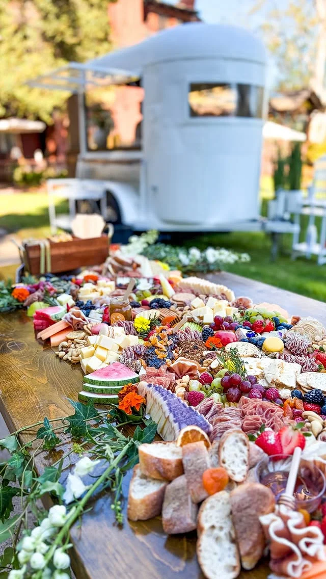 Colorful grazing table with cheeses, fruits, breads and sweets on layered boards