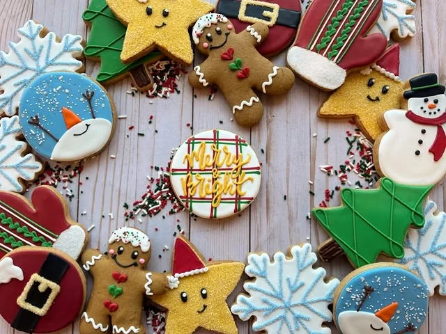 Circle of assorted decorated Christmas cookies arranged on a wooden plank