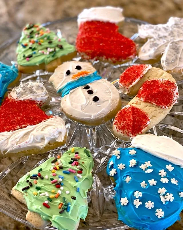 Nine decorated holiday sugar cookies arranged on a glass serving platter
