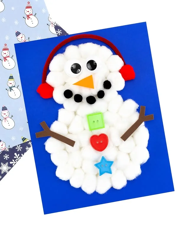 Cotton ball snowman craft with earmuffs and button decorations on blue card