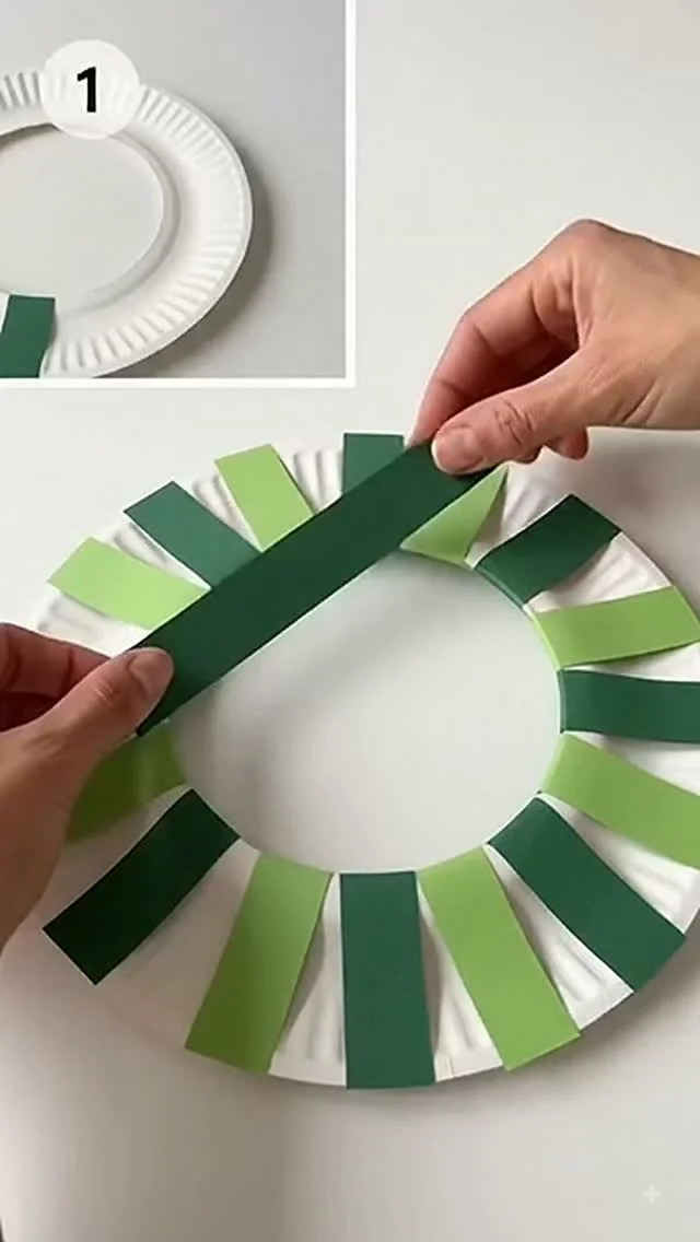 Paper strip wreath craft with green paper strips on a paper plate ring