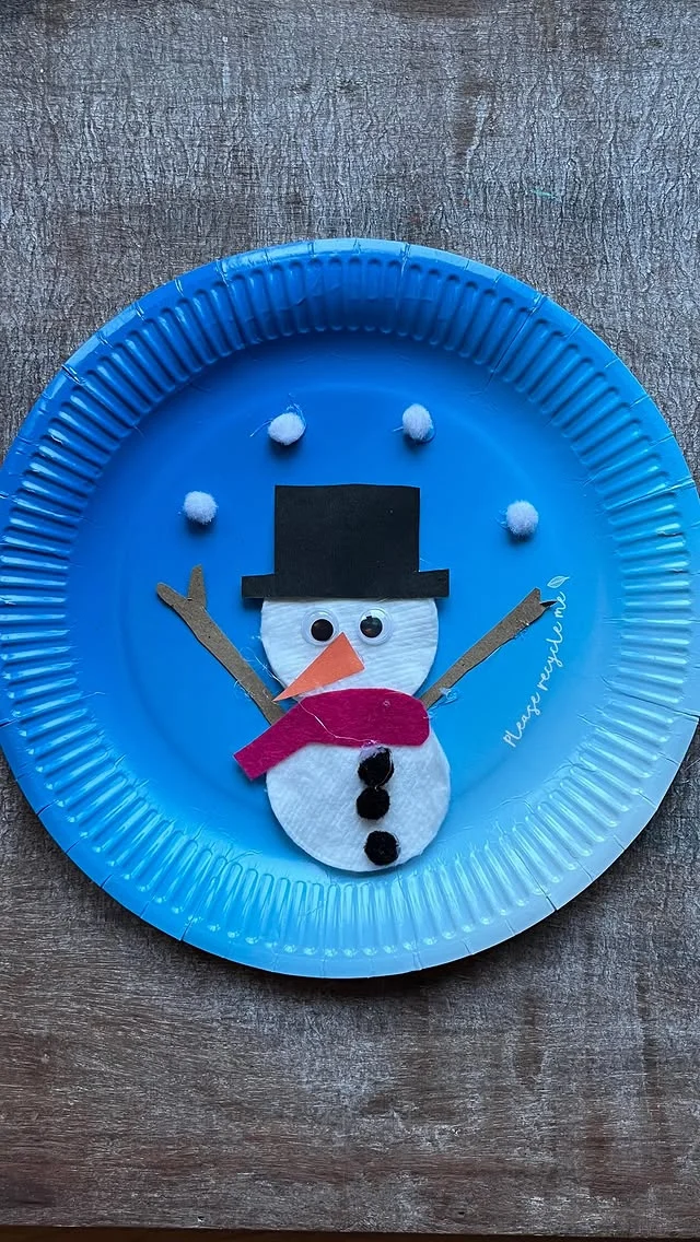 Paper plate snowman portrait with black hat and red scarf on blue plate
