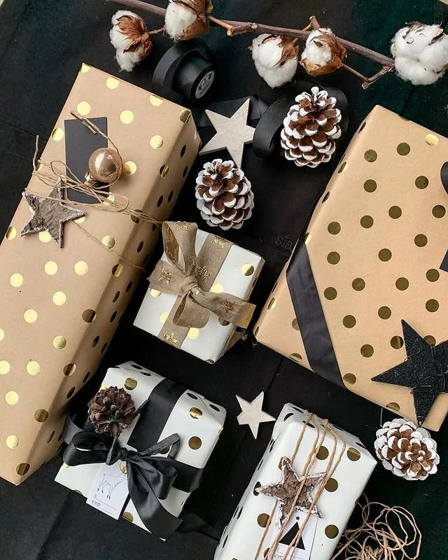 Gifts wrapped in gold polka dot paper with pinecones and star decorations