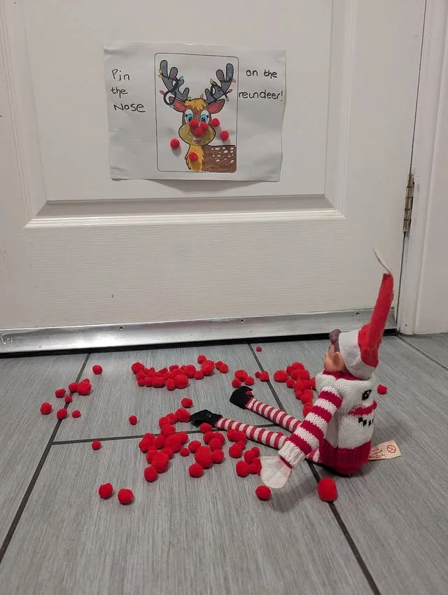 Pin the nose on the reindeer door game with red pom poms scattered on the floor