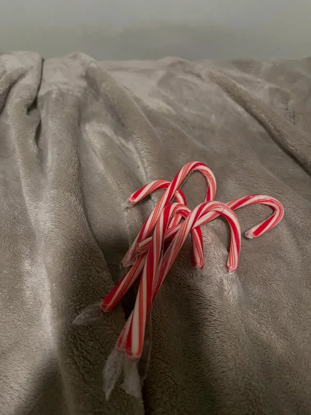 Red and white candy canes on a gray fleece blanket