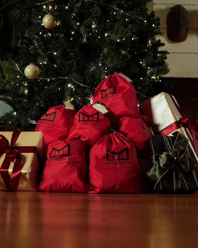Red gift bags and wrapped presents under a Christmas tree