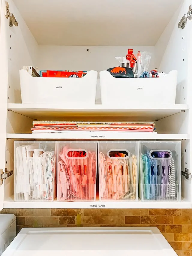 Labeled bins for gifts and tissue paper in a wrapping supply cabinet