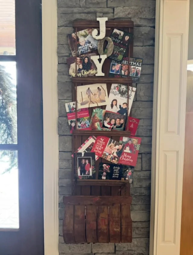 Christmas cards displayed on a sled-shaped card holder with JOY letters