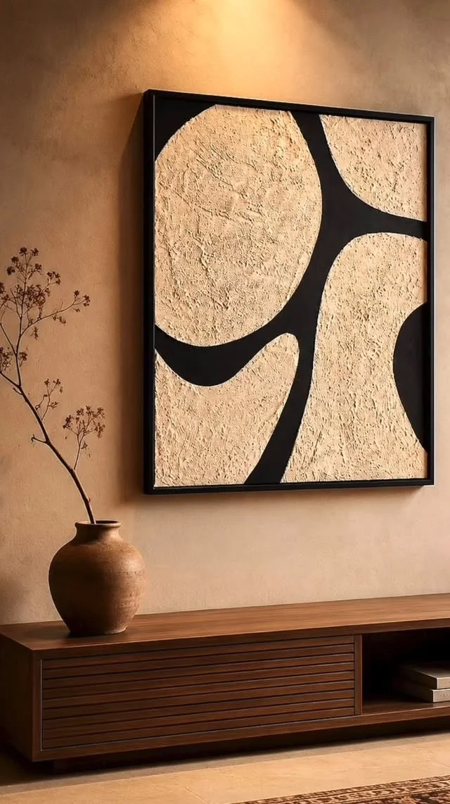 Framed textured abstract canvas with large beige shapes and bold black curves hanging above a wooden console