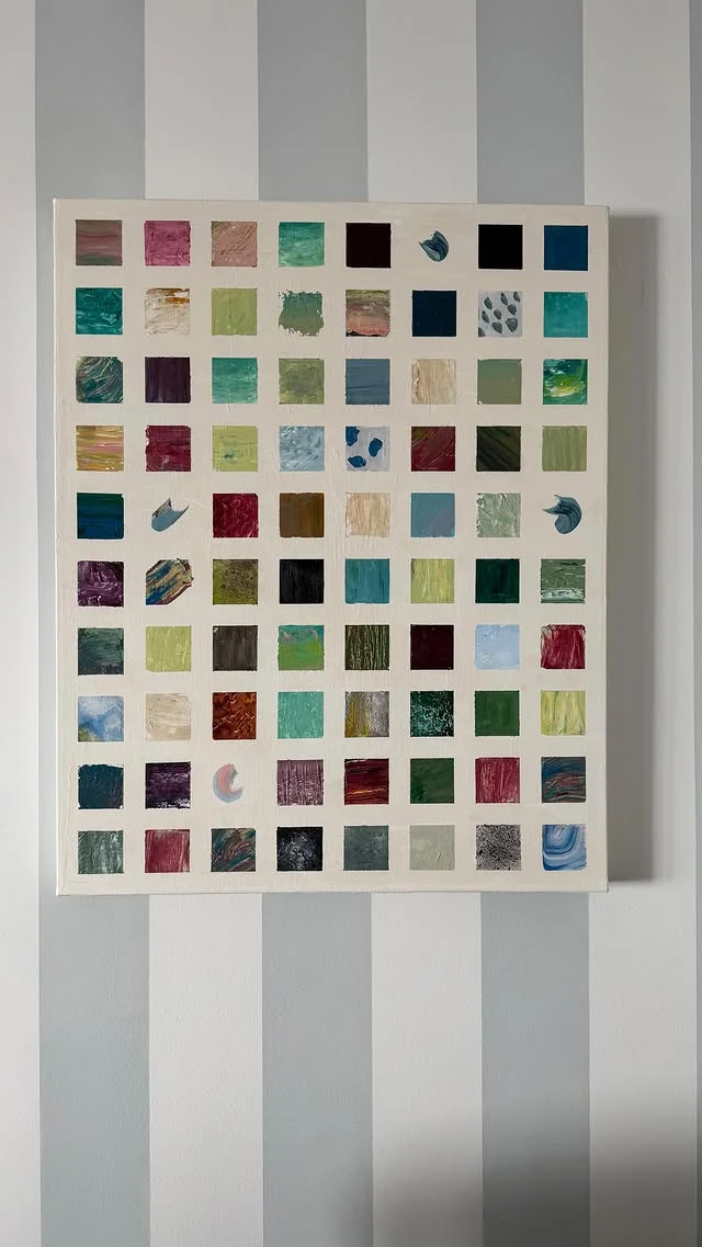 Colorful abstract painting made of many small painted squares in a grid on a striped wall