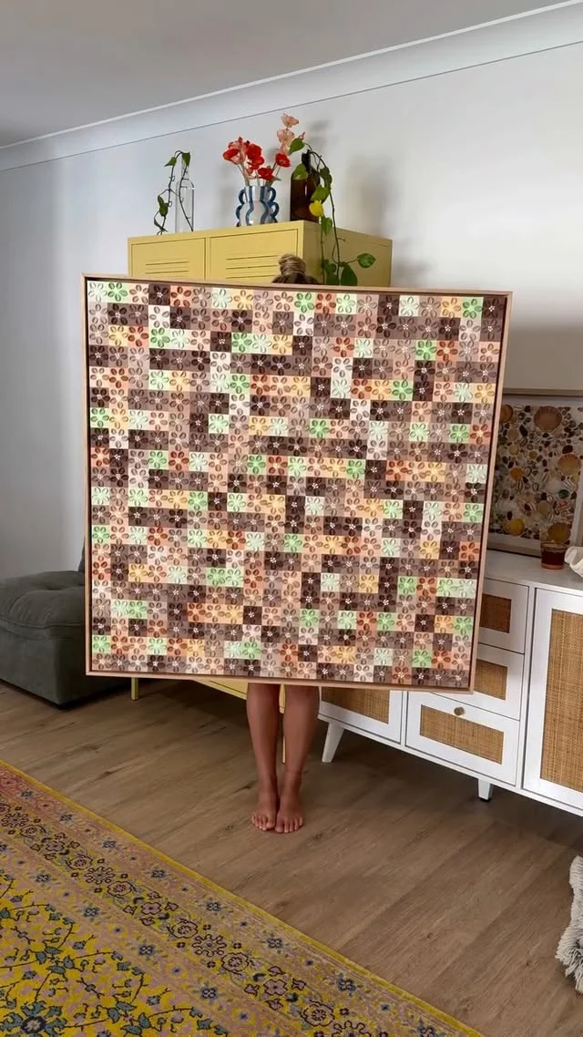 Person holding a large patchwork textured canvas covered in small beige and brown squares