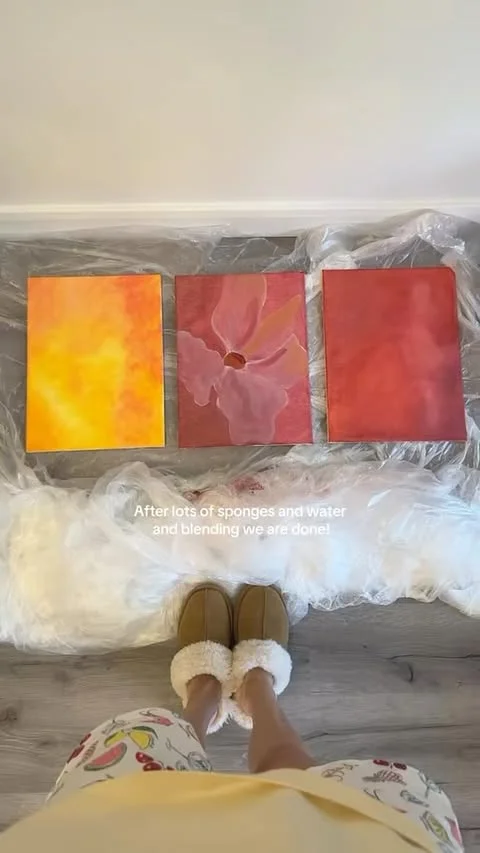Three small abstract canvases in orange and red gradients laid out on a protected floor