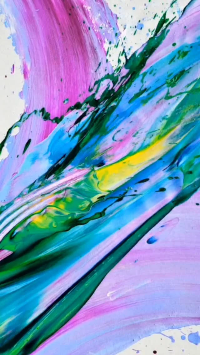 Close view of swirling ribbons of pink, blue, green and yellow paint on canvas