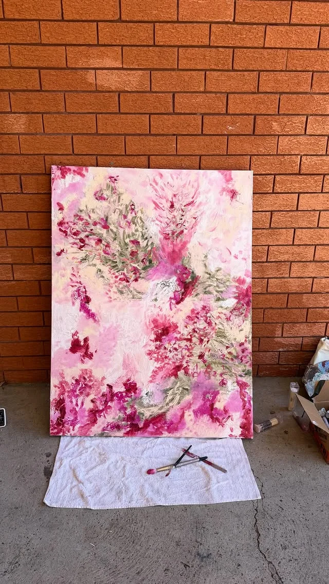 Large pink and white marbled abstract canvas leaning against a brick wall outdoors