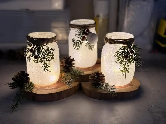Frosted mason jar lanterns with twine and winter greenery