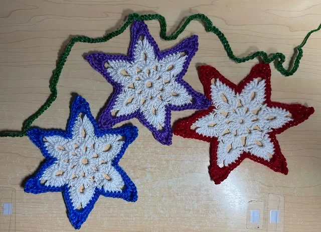 Crocheted star ornaments in blue, purple and red