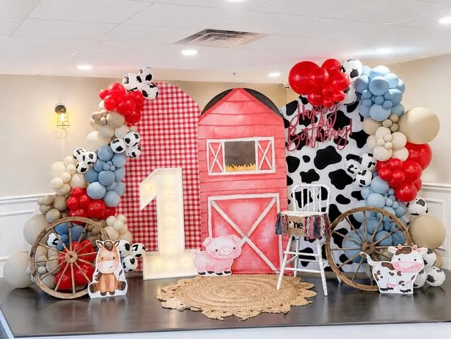 Farm first birthday stage with red barn and cow print wall