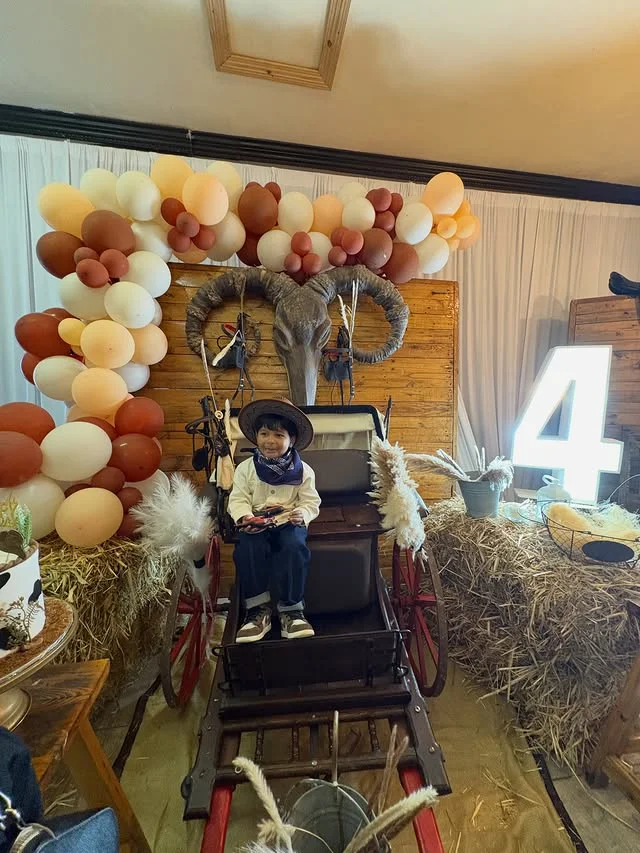 Cowboy birthday party with wooden wagon, hay bales and balloon arch