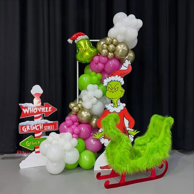 Grinch photo setup with a cardboard cutout and green furry sleigh