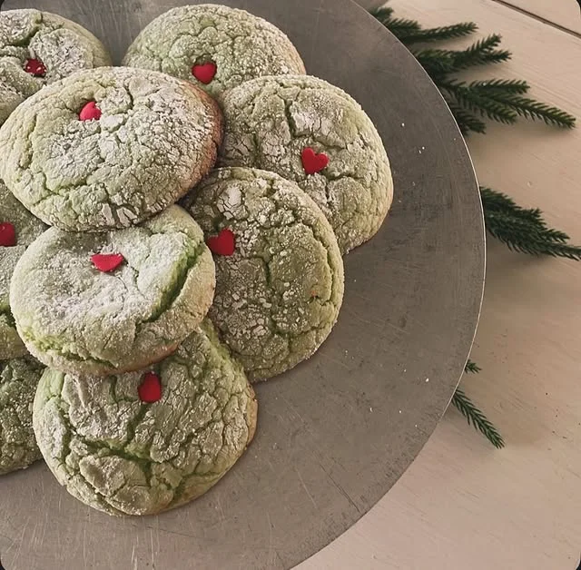Green crinkle cookies with red heart candies on a cake stand