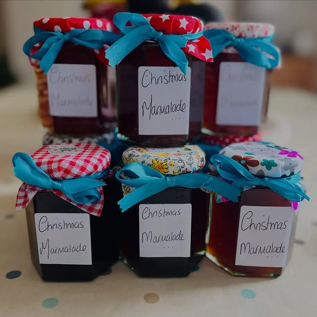 Small jars of Christmas marmalade with fabric covers and blue ribbon bows