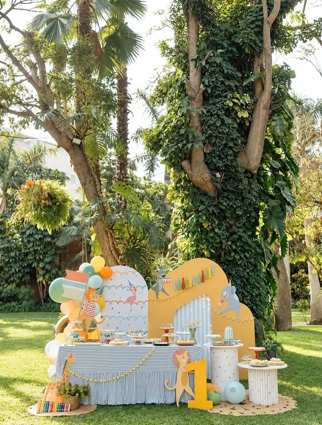 Outdoor dessert table with safari backdrop, animal figures and treats