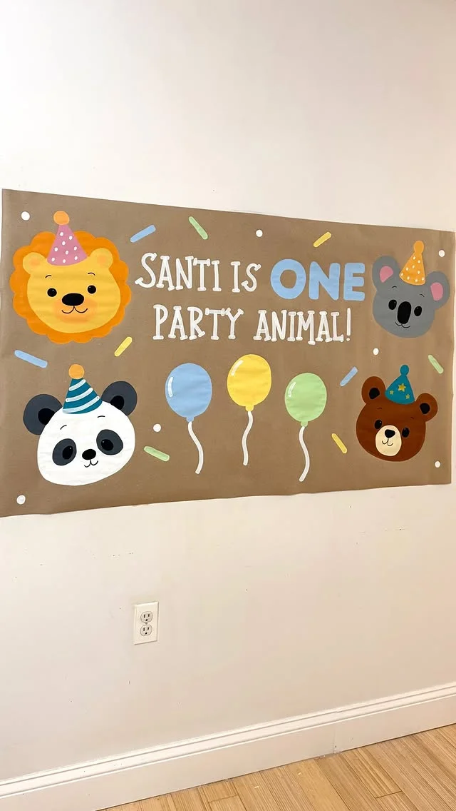 Hand painted banner reading Santi Is One Party Animal with cartoon animal faces