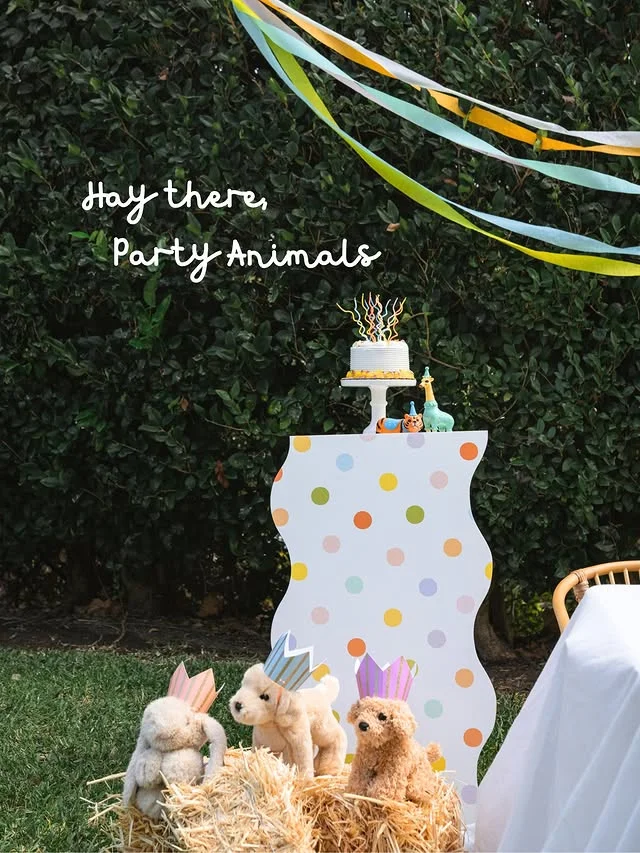 Hay bales with plush animals in crowns beside a spotted party backdrop