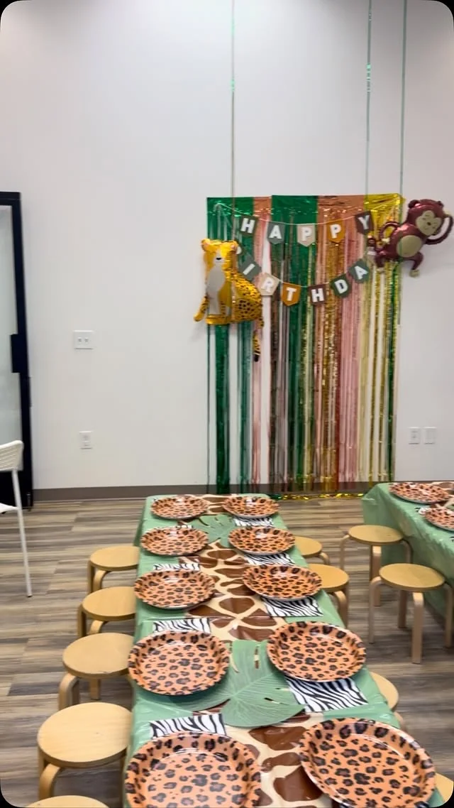 Indoor safari party room with animal print tables, stools and a balloon backdrop