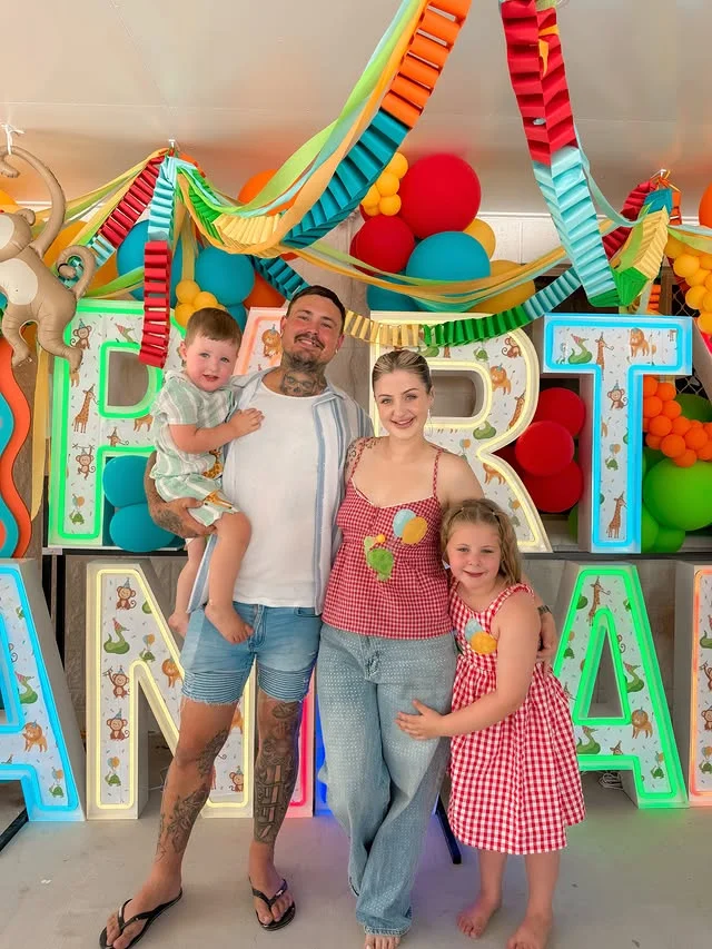 Large glowing PARTY ANIMAL letters with balloons and streamers behind a family
