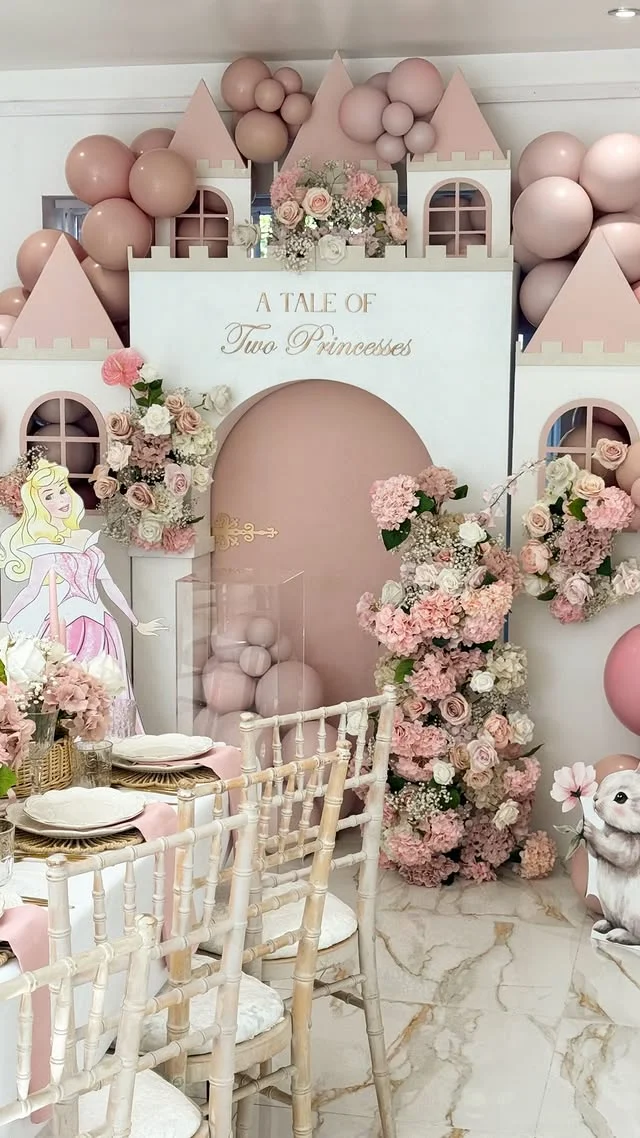 White and pink castle facade with gold script reading A Tale of Two Princesses