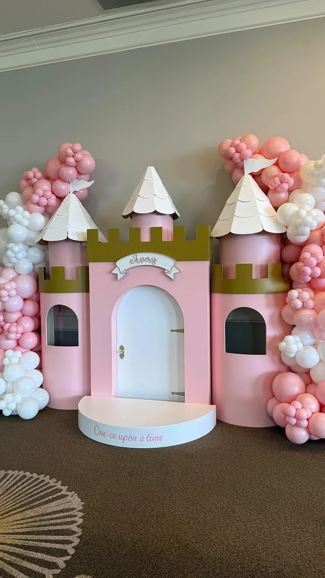 Freestanding pink castle facade with two towers and white scalloped roofs