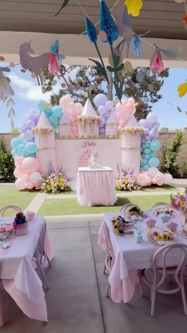 Outdoor backyard pastel castle backdrop with a pink castle and balloons