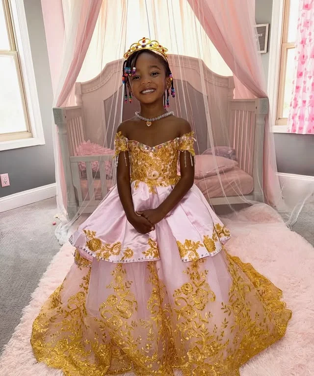 Young girl wearing a pink and gold princess gown with a gold crown