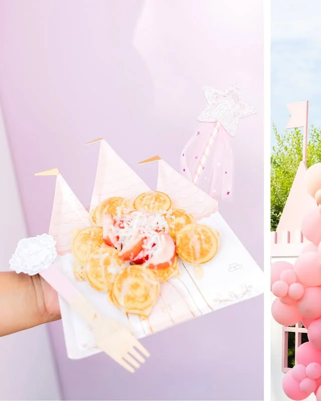 Hand holding a castle shaped plate of mini pancakes with strawberries and a star wand