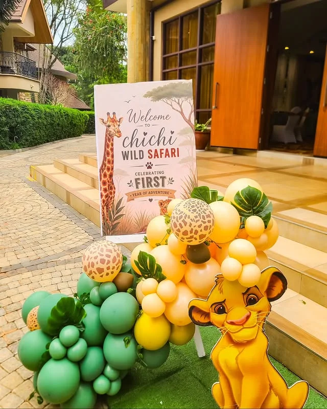Welcome sign for a wild first birthday with green and yellow balloons and a lion cutout