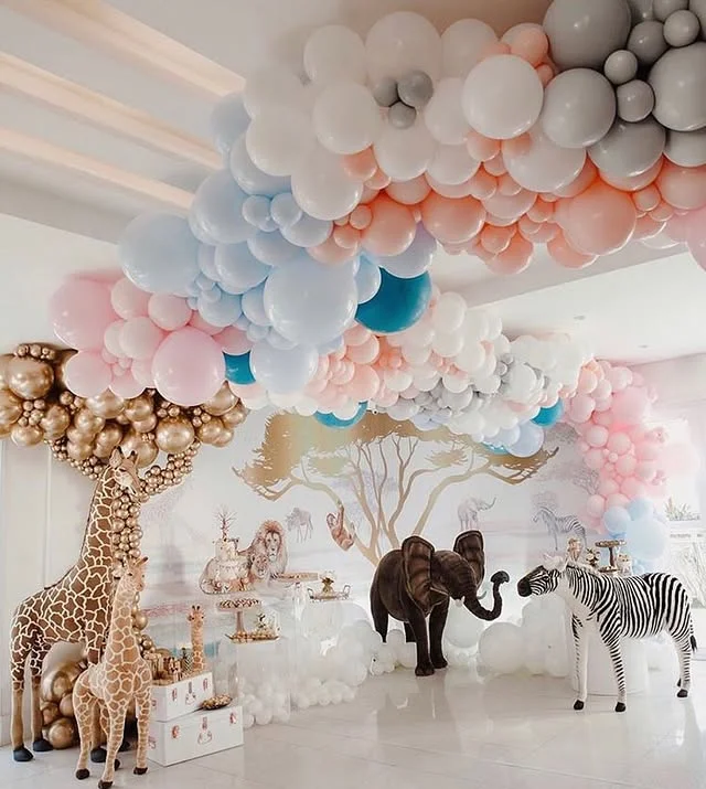 Pastel balloon canopy over a party room with giraffe, zebra and elephant figures