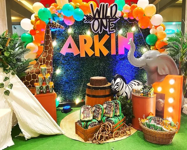 Bright Wild One backdrop with a name sign, lit letters and a dessert table