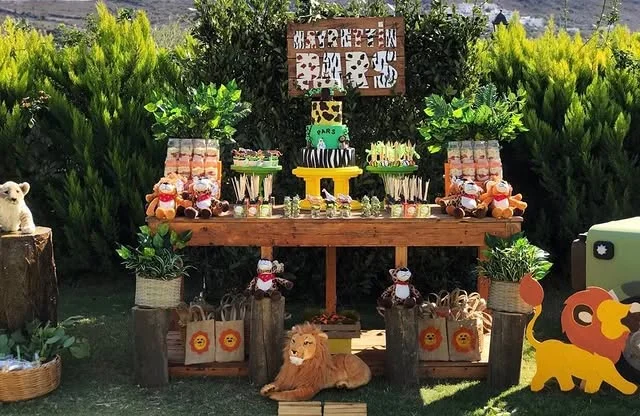 Outdoor garden dessert table with a tiered cake, treat jars and animal figures