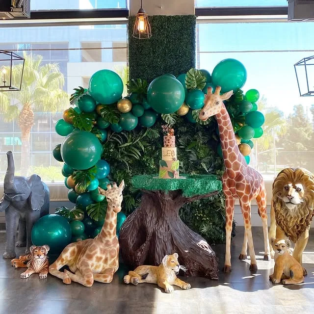 Tree stump cake stand with emerald balloons and standing giraffe, lion and elephant figures