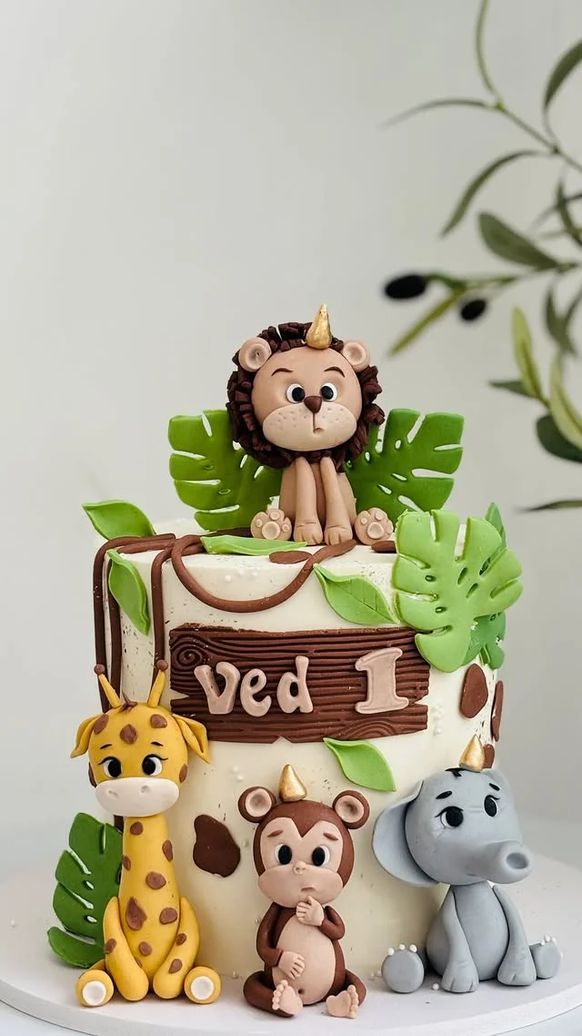 Single tier cake topped with a lion figure and giraffe monkey and elephant figures