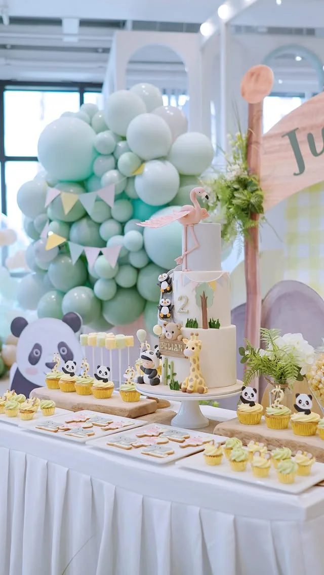 Panda themed dessert table with cupcakes and a balloon garland