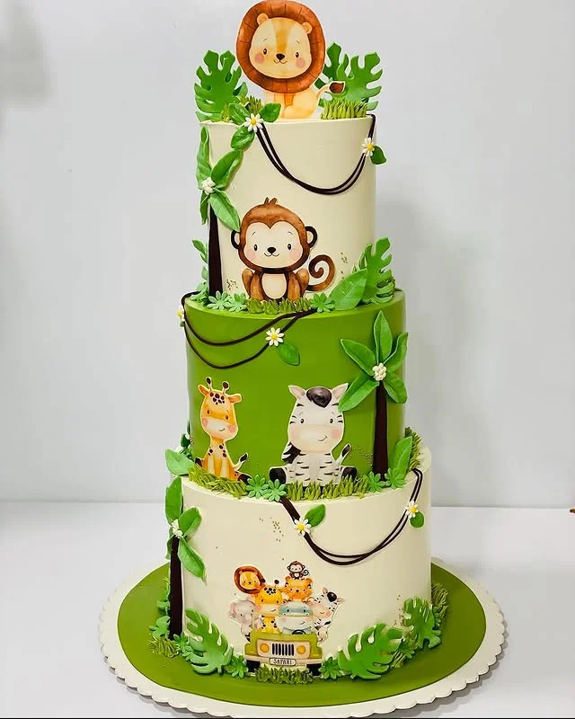 Three tier green jungle cake with lion monkey giraffe and zebra figures